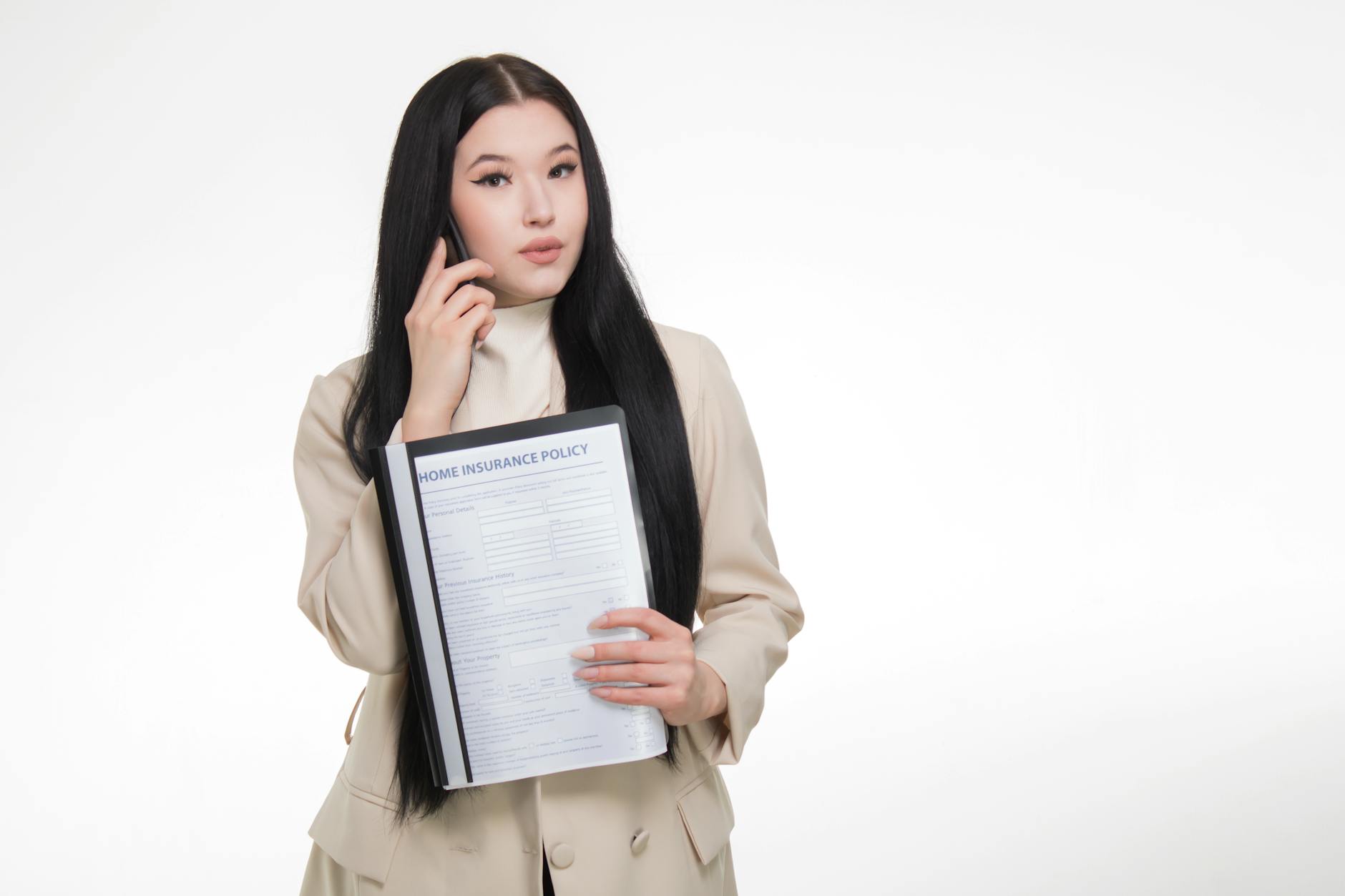 pexels-photo-7736030 - Eric Felt Insurance Asian woman in business attire holding home insurance policy while on a phone call.